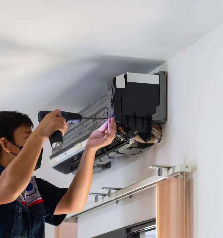 Engineer repairing the internal parts of a wall-mounted air conditioning unit in Bristol
