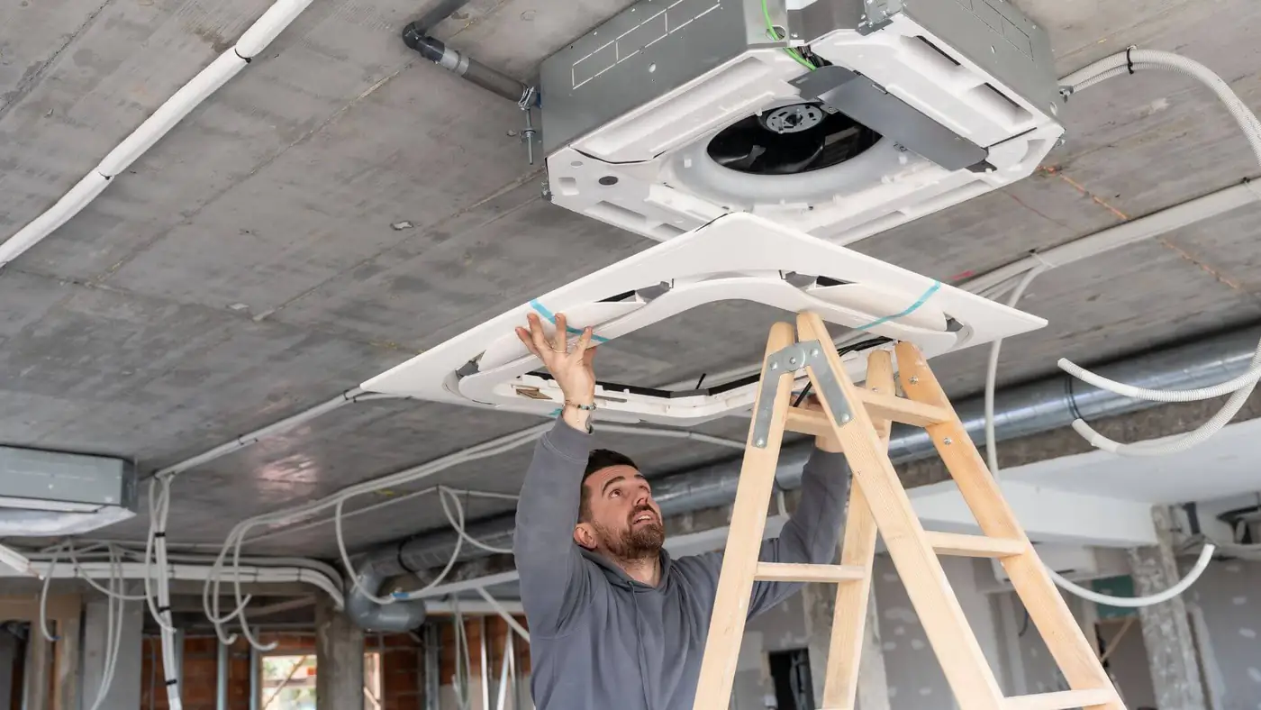 Ceiling cassette servicing in Bristol Engineer on a ladder working on a ceiling cassette air conditioning unit in Bristol