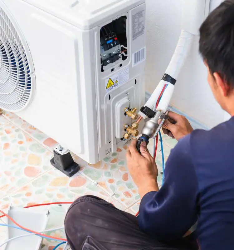 Engineer connecting refrigerant pipework to a home air conditioning outdoor unit in Bristol