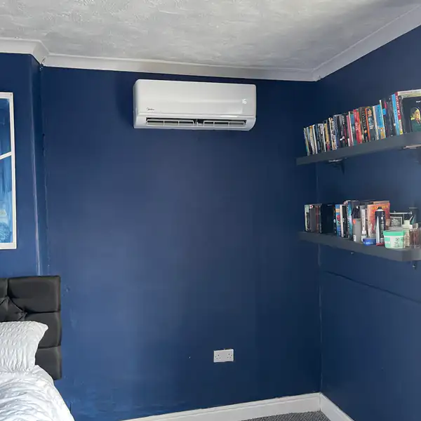 Wall-mounted split air conditioning in a navy bedroom in Bristol